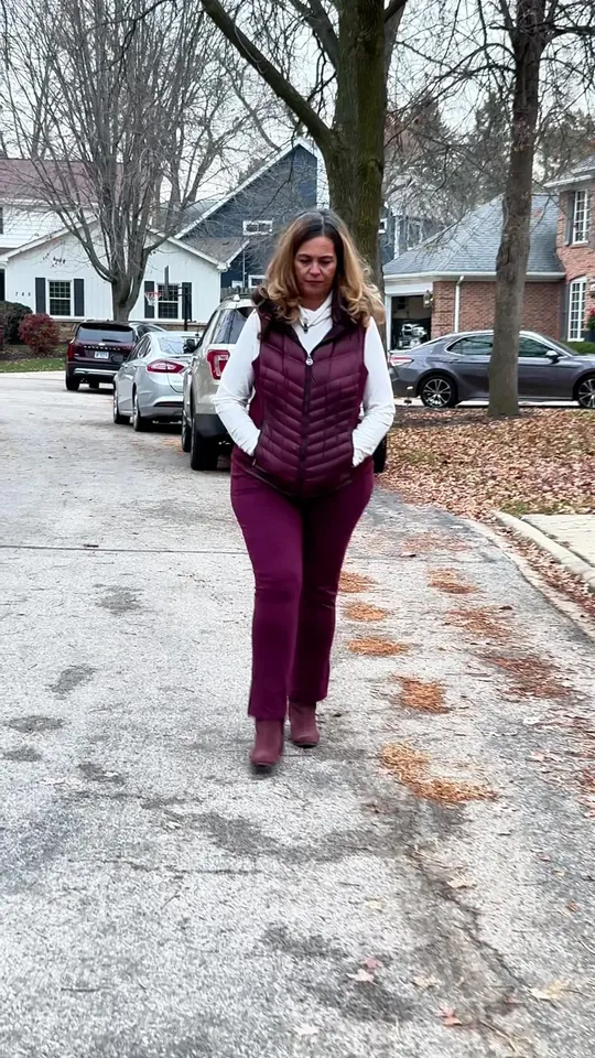 A woman in a purple vest walking down a suburban driveway