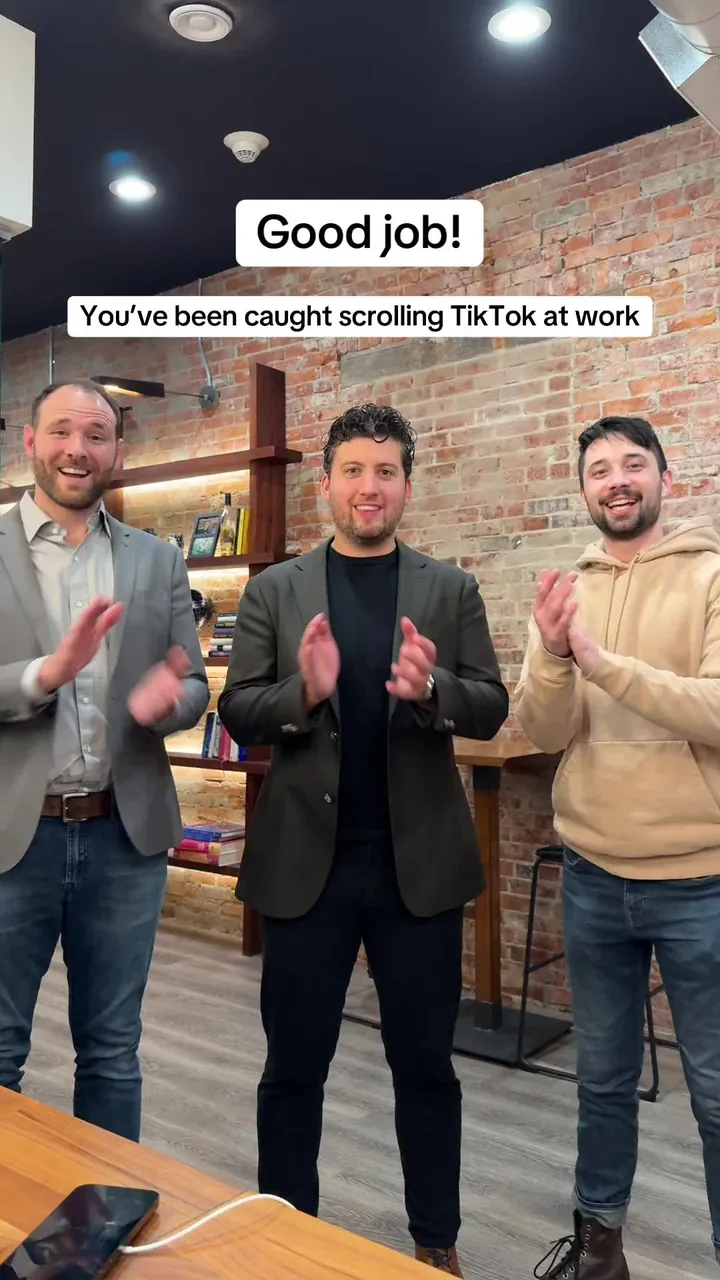 Three men in an office applauding, captioned Good job! You've been caught scrolling TikTok at work